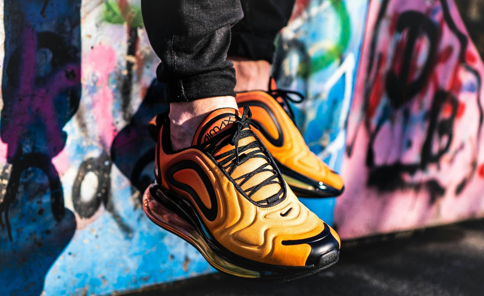 Bold sneakers stand out against a colorful graffiti wall, showcasing modern street style.